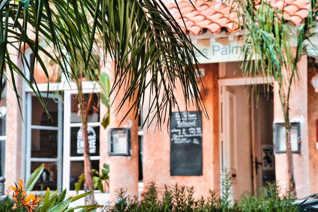 a building with a palm tree in front of it at Hotel Les Palmiers in Sainte-Maxime