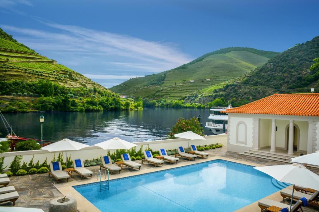 uma piscina com cadeiras e vista para um rio e montanhas em The Vintage House - Douro no Pinhão