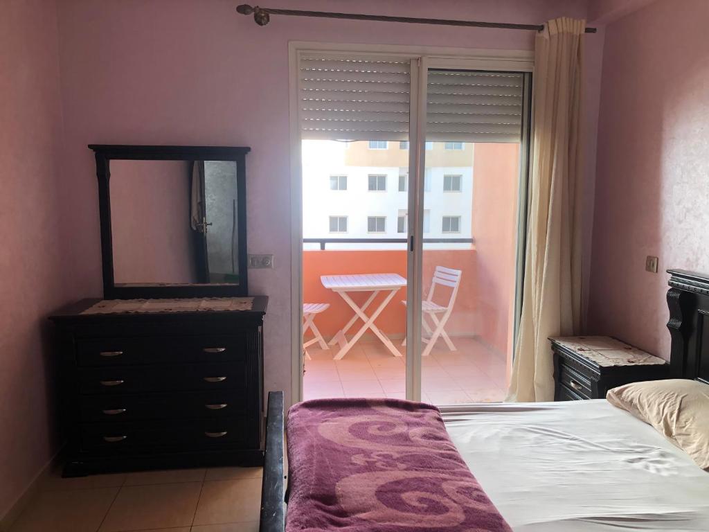 - une chambre avec un lit, une commode et un miroir dans l'établissement Appartement, à Agadir