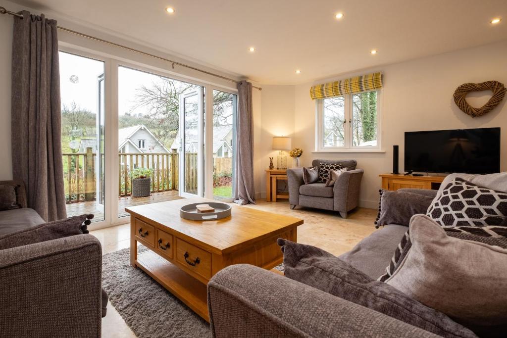 a living room with a couch and a table and a tv at Trewhiddle Villa 24 in St Austell