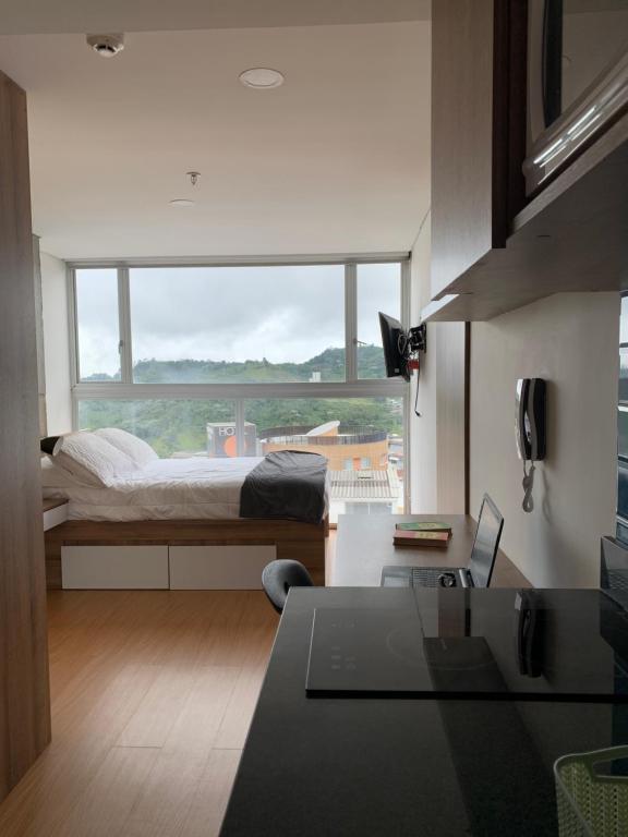 マニサレスにあるUlivin Apartaestudios Manizalesのベッドルーム1室(ベッド1台、大きな窓付)