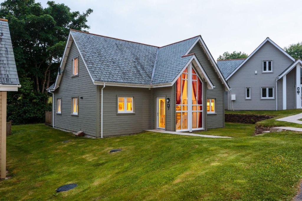 a gray house with a red door on a yard at Trewhiddle Villa 18 in St Austell