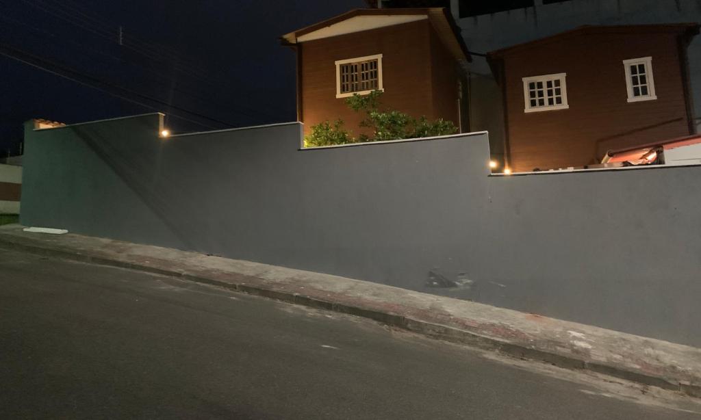 uma cerca branca com luzes ao lado de uma rua em Suítes Cabanas Coral em Serra