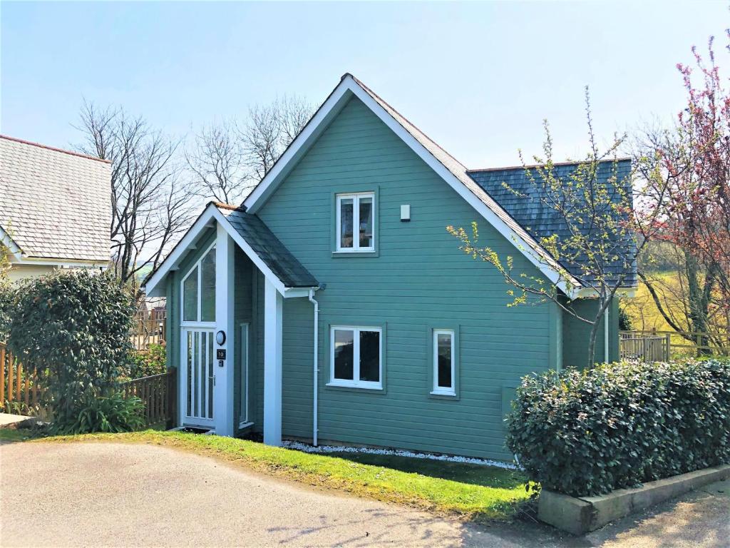a blue house with a white door in a yard at Trewhiddle Retreat V10 by Together Travel - Luxury 4-Bedroom Villa in St Austell