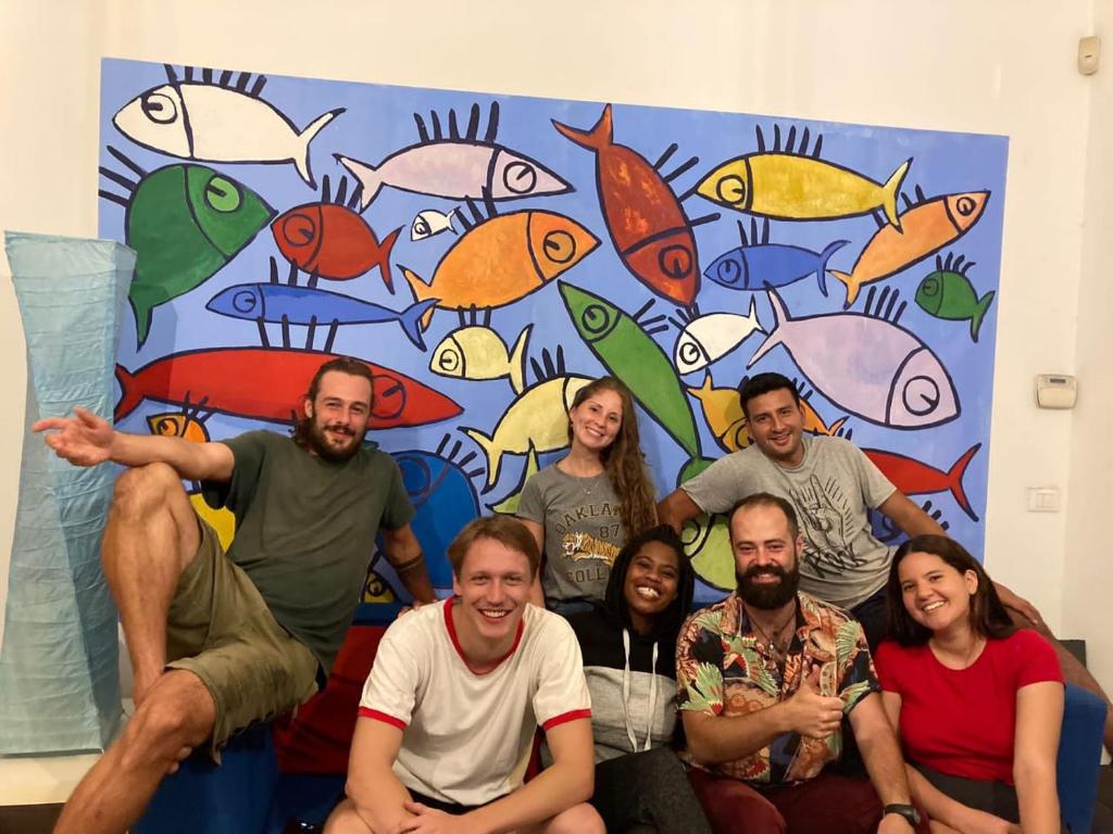 eine Gruppe von Menschen, die auf einer Couch vor einer Wand sitzen in der Unterkunft Balarm Hostel - Youth Hostel age limit 18-50 in Palermo