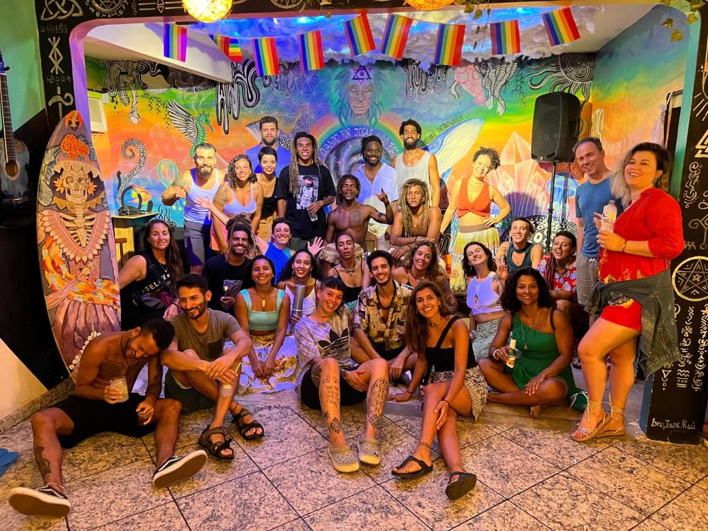 a group of people posing for a picture in front of a mural at Chamos Hostel Cultural in Arraial do Cabo