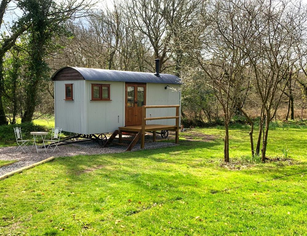 ein kleiner Schuppen mit einer Bank auf einem Feld in der Unterkunft Lilliput - Delightful 1-bedroom shepherd's hut in Holsworthy