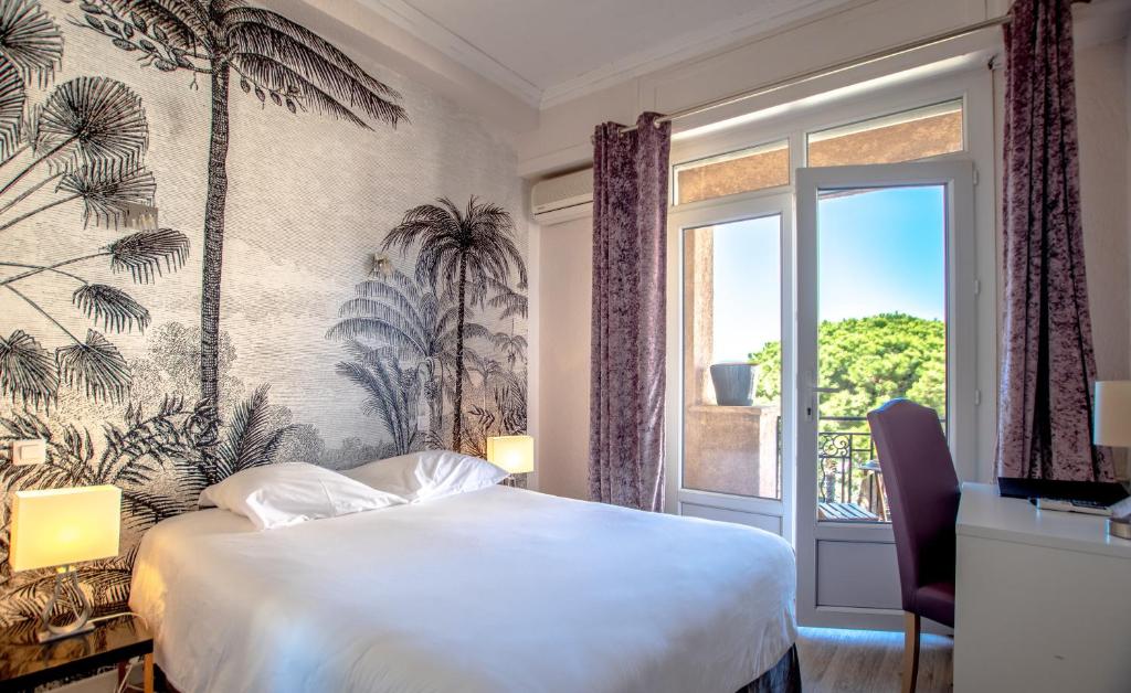 a hotel room with a bed and a window at Hotel Les Palmiers in Sainte-Maxime