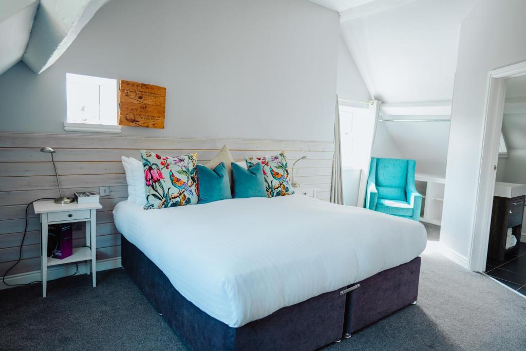 a bedroom with a large bed and a blue chair at The Fox Inn in Stourbridge