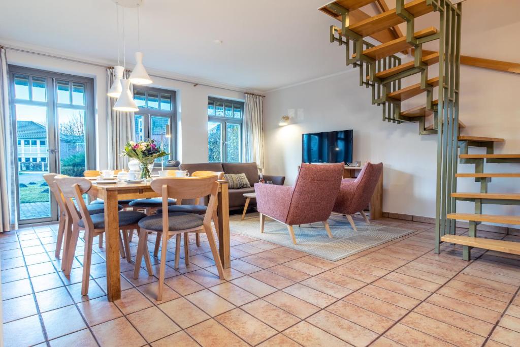 a dining room and living room with a table and chairs at Ferienhaussiedlung Strandperlen Buchenhof 2a (Typ VIII) in Wustrow