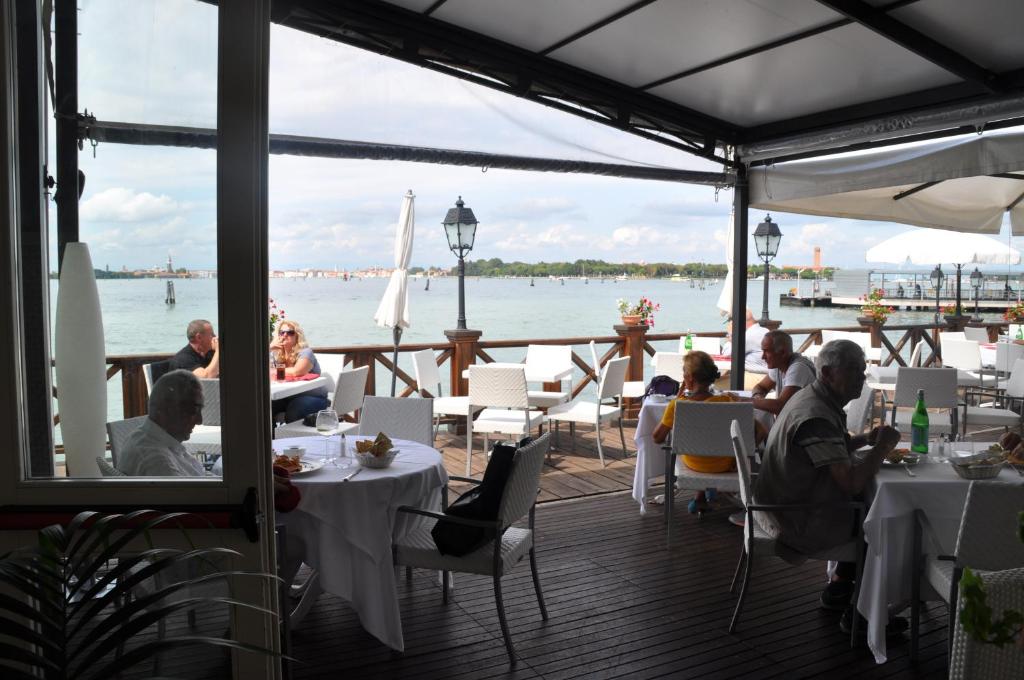 a group of people sitting at tables on a deck at Hotel Villa Laguna in Venice-Lido