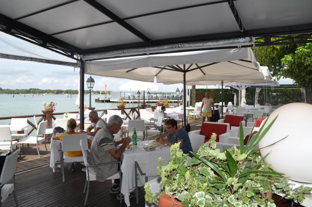 a group of people sitting at tables on a deck at Hotel Villa Laguna in Venice-Lido