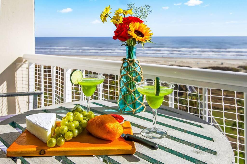 uma mesa com uma bandeja de comida e bebidas numa varanda em Beachfront Sunrise  em Galveston