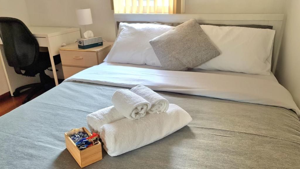 a bed with two towels and a box of toys at Nice room close to Melb Airport in Melbourne