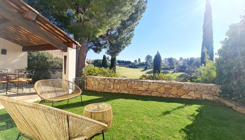 a yard with chairs and a stone wall at SUPERBE VILLA-DOMAINE AVEC GOLF PISCINE ET TENNIS in Saint-Cyr-sur-Mer