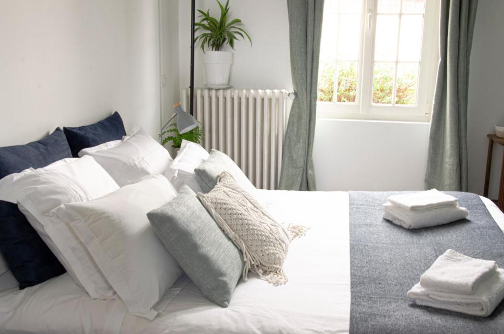 um quarto com uma cama branca com almofadas e uma janela em Au 41 - le calme à 5 min d'Auxerre em Saint-Georges-sur-Baulche