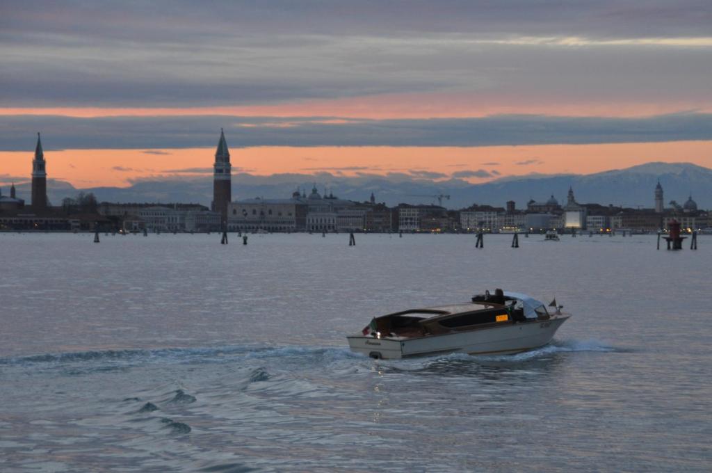 a boat in the water with a city in the background at Hotel Villa Laguna in Venice-Lido