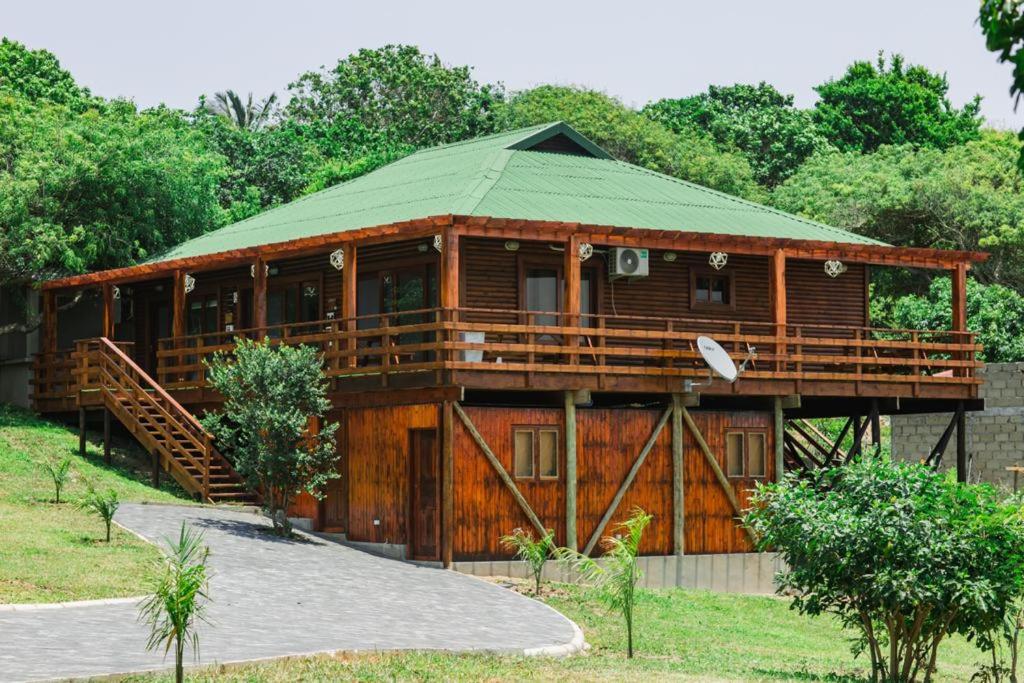 a large wooden house with a green roof at Anna Beach Village in Ponta do Ouro