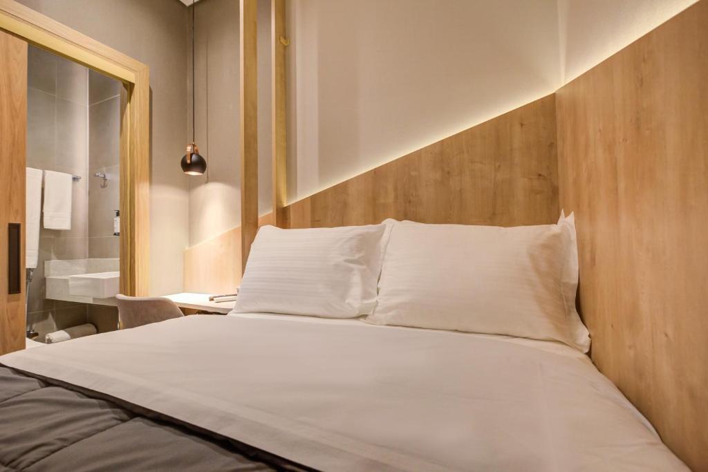 Bett mit weißer Bettwäsche und Kissen in einem Zimmer in der Unterkunft Fast Sleep Suites by Slaviero Hoteis - Hotel dentro do Aeroporto de Guarulhos - Terminal 2 - desembarque oeste in Guarulhos