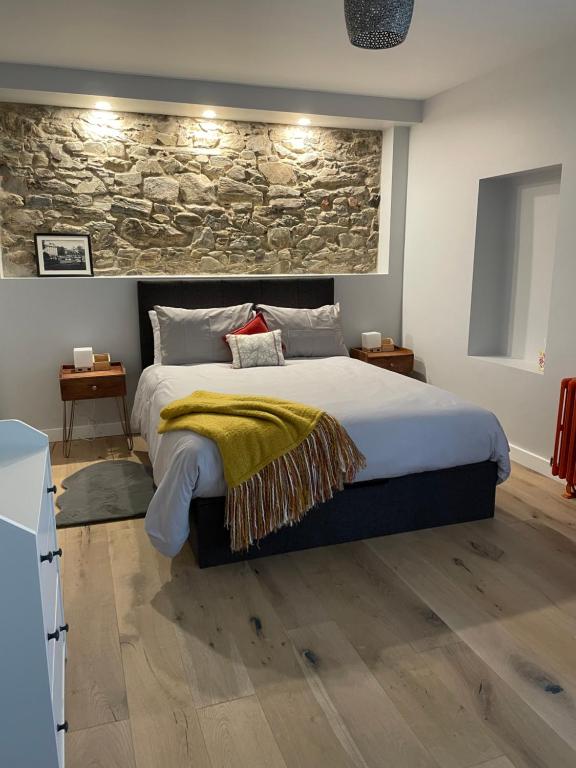 a bedroom with a large bed with a stone wall at Woodstock Courtyard in Inistioge