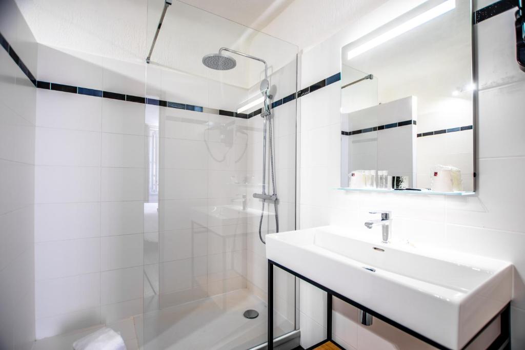 a white bathroom with a sink and a shower at Hotel Les Palmiers in Sainte-Maxime