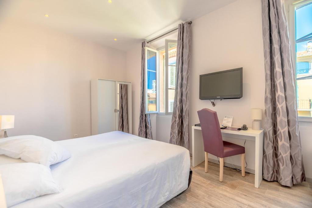 a bedroom with a bed and a desk and a tv at Hotel Les Palmiers in Sainte-Maxime