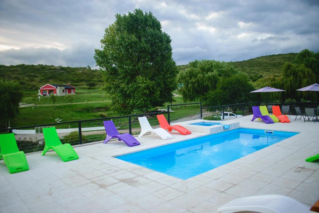 a pool with colorful lounge chairs next to it at El Zuriaco in Santa Rosa de Calamuchita