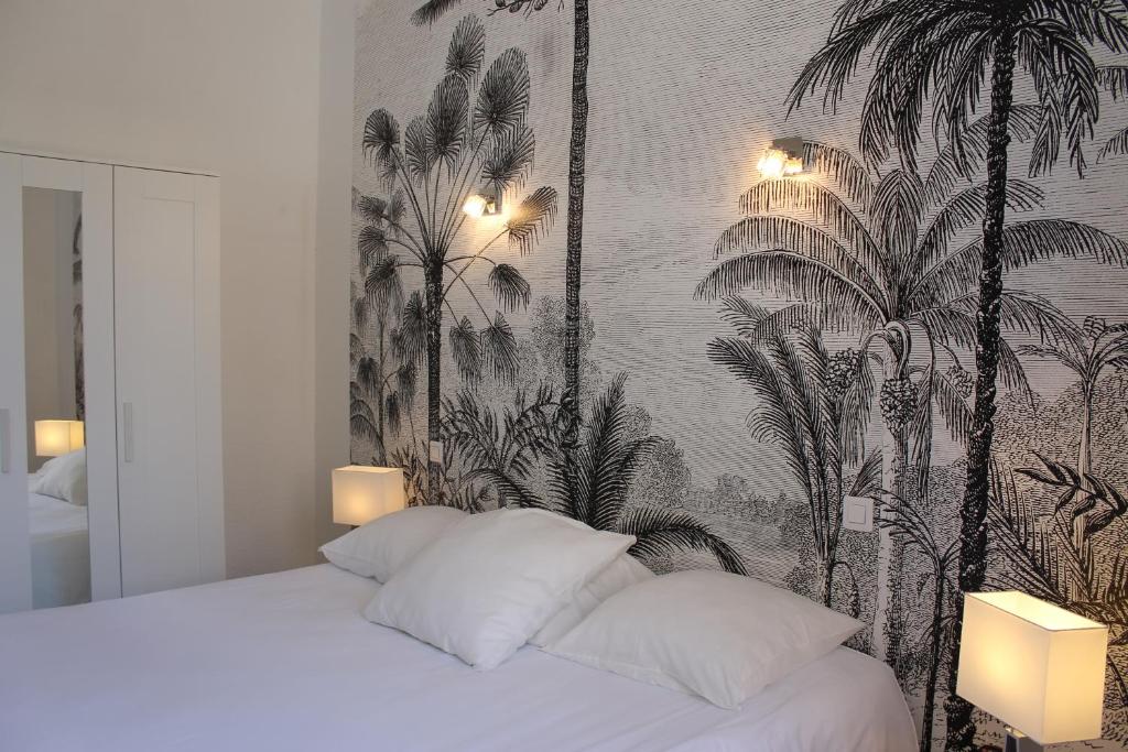 een slaapkamer met een bed met behang met palmbomen bij Hotel Les Palmiers in Sainte-Maxime