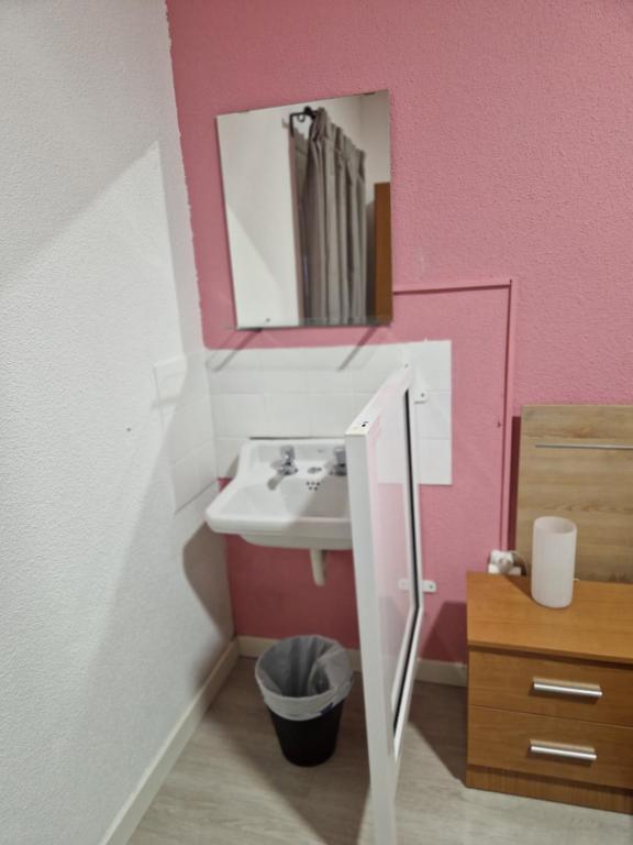 y baño con lavabo y espejo. en PENSION ZEUS, en Valladolid
