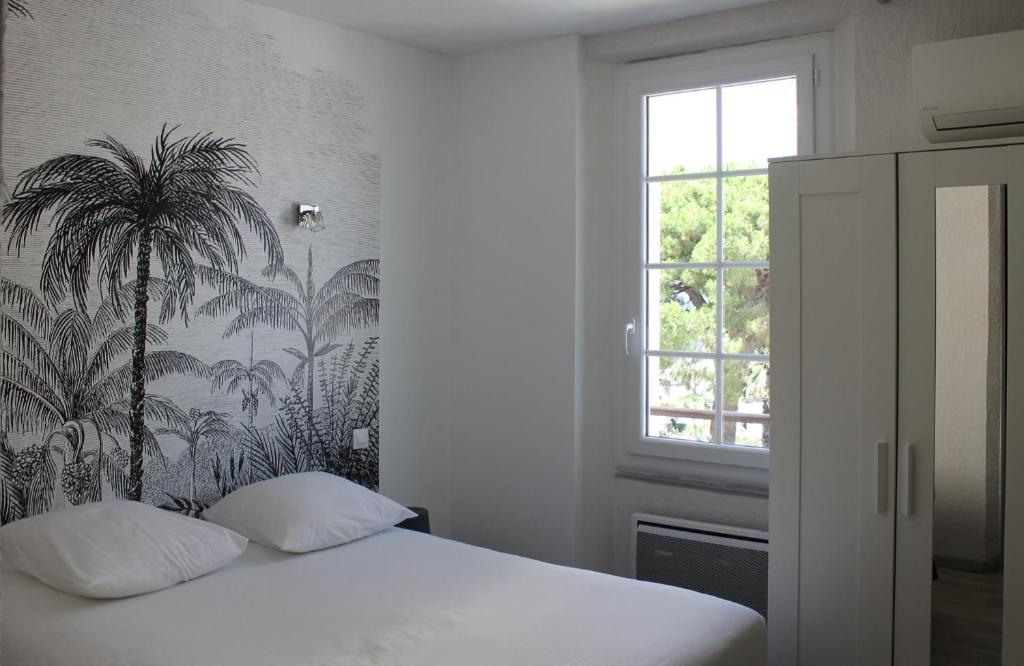 a bedroom with a bed with a palm tree wallpaper at Hotel Les Palmiers in Sainte-Maxime