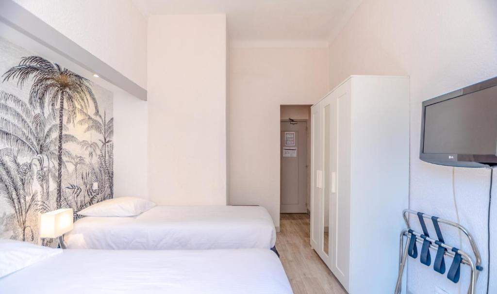 a hotel room with two beds and a flat screen tv at Hotel Les Palmiers in Sainte-Maxime