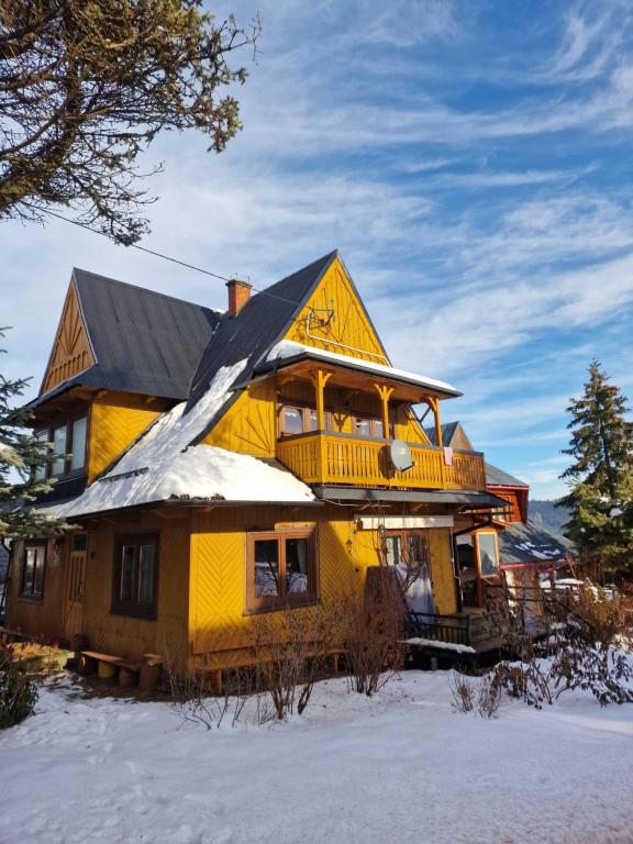 una gran casa amarilla con nieve en el techo en Stara chałupa, en Murzasichle