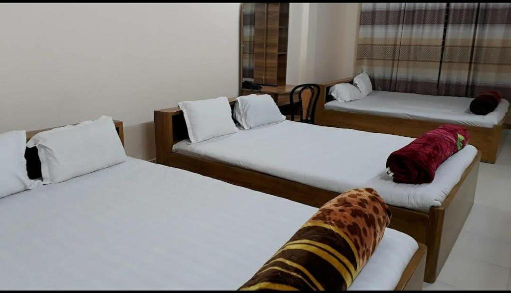 Habitación con 3 camas y sábanas blancas. en Hotel Square Park, en Rāngāmāti