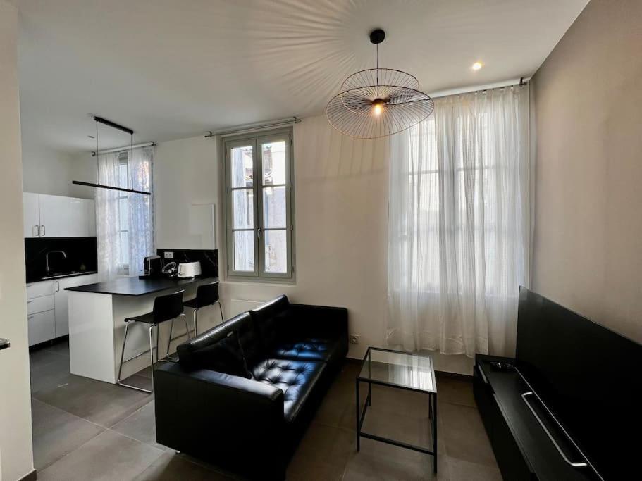 a living room with a black couch and a kitchen at Le Sainte-Ursule in Montpellier