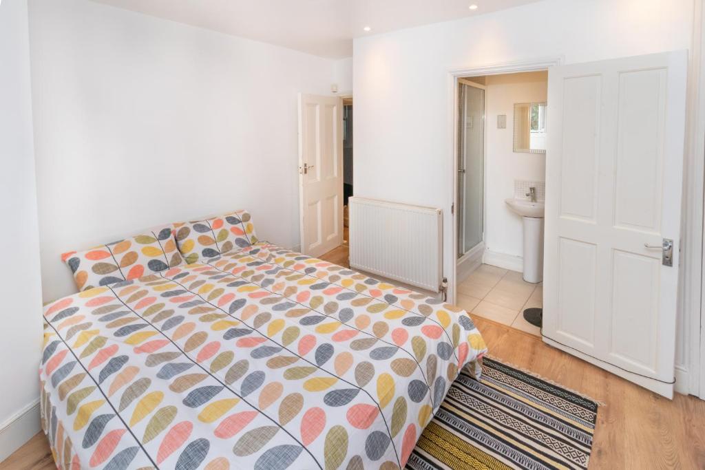a bedroom with a large bed and a bathroom at Cosy flat in leafy London in London