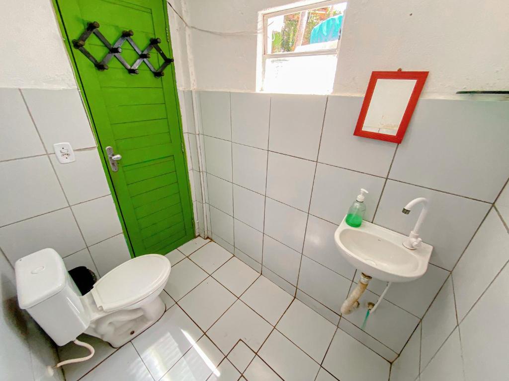 a bathroom with a green door and a toilet and sink at Padang Hostel in Pipa