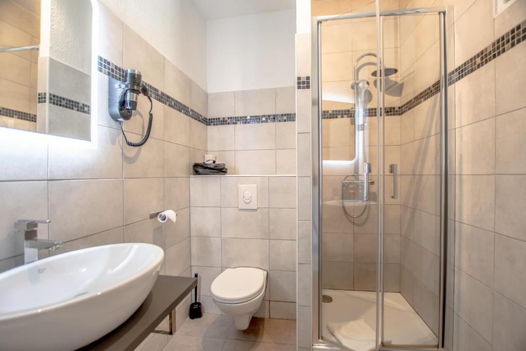 a bathroom with a shower and a toilet and a sink at Hotel Les Palmiers in Sainte-Maxime