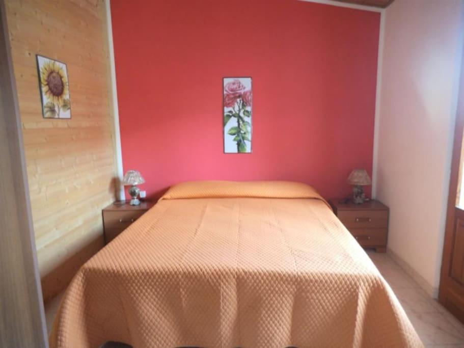 um quarto com uma cama com uma parede vermelha em Mansarda M&M SX em Castellammare del Golfo
