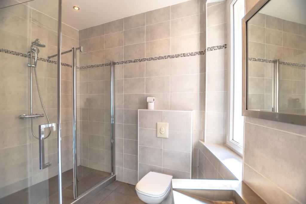 a bathroom with a shower stall and a toilet at Hotel Les Palmiers in Sainte-Maxime
