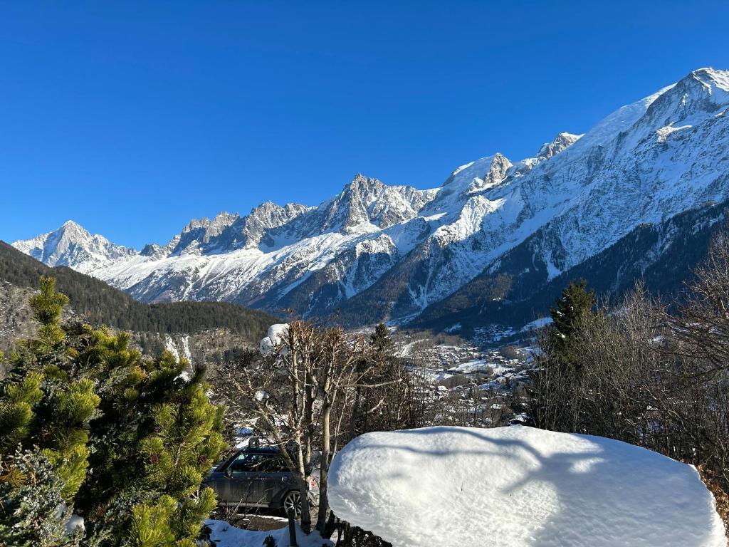 eine schneebedeckte Bergkette mit einem Auto vor der Unterkunft in der Unterkunft Logement avec jardin et vue panoramique MontBlanc in Les Houches