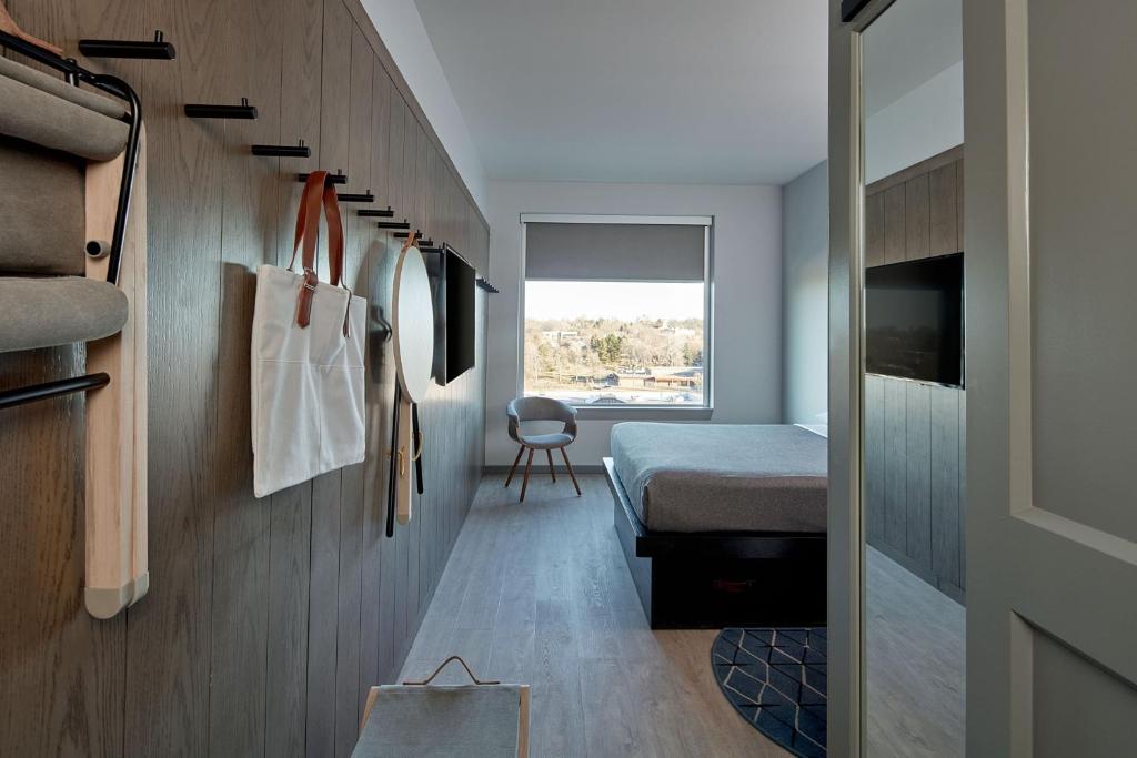 a small bedroom with a bed and a hallway at MOXY Denver Cherry Creek in Denver