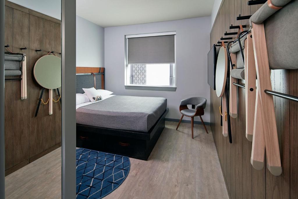 a small bedroom with a bed and a window at MOXY Denver Cherry Creek in Denver