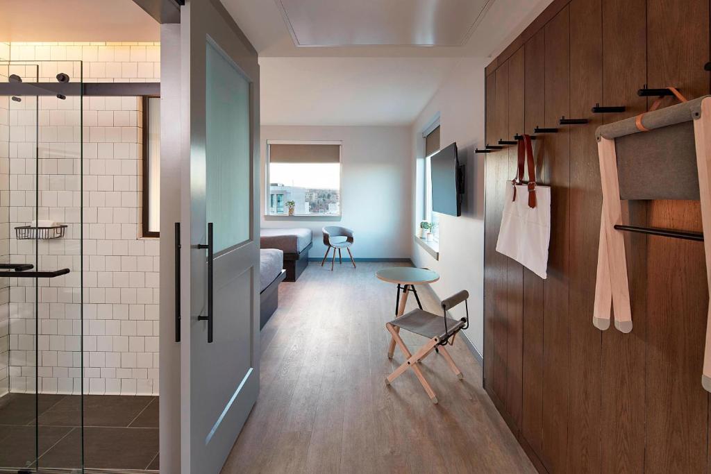 a room with a bathroom with a shower and a chair at MOXY Denver Cherry Creek in Denver