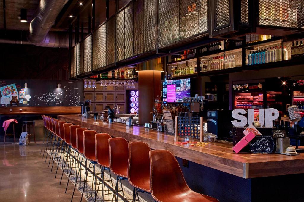 a bar with a row of brown leather chairs at MOXY Denver Cherry Creek in Denver
