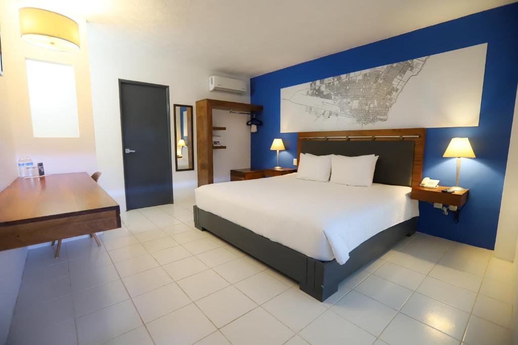 a bedroom with a large bed and a desk in it at TRYP by Wyndham Chetumal in Chetumal
