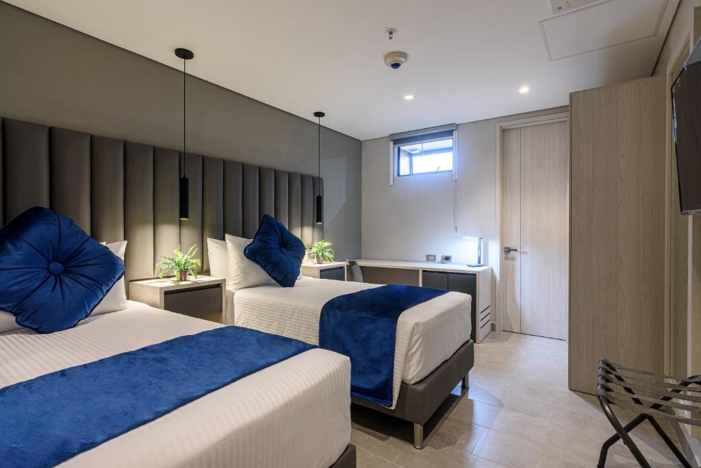 een hotelkamer met 2 bedden met blauwe kussens bij 4 Sur Hotel in Medellín