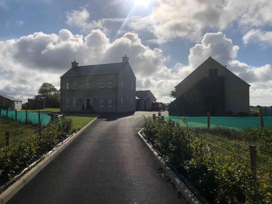 a road leading to a large building with the sun in the sky at Lily’s Loft Bushmills in Bushmills