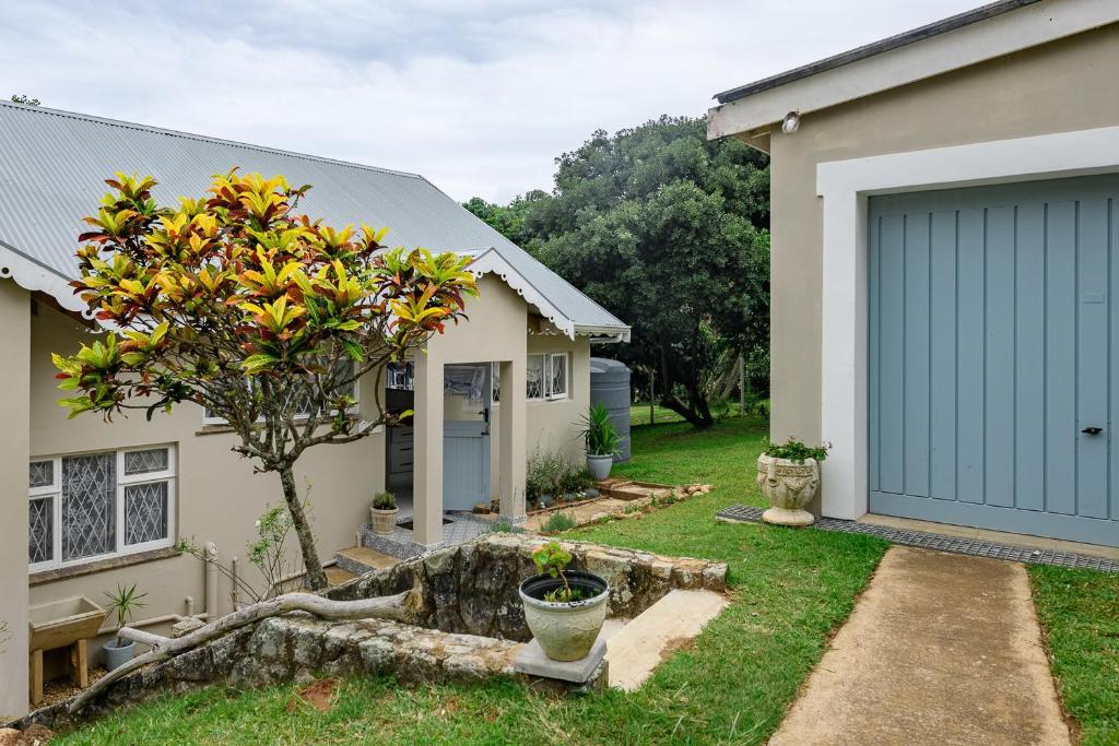 a house with a blue garage door and a tree at Golf Beach and Sea in Southbroom