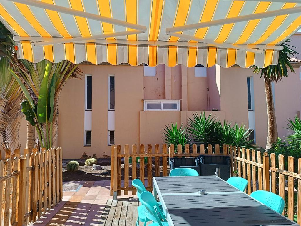 a patio with a table and chairs under a pergola at Green Oasis Maspalomas garden 11 in Maspalomas