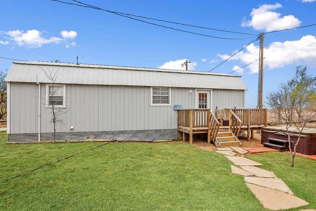 a white building with a porch and a yard at Palo Duro Canyon Texas - Cowboy Cabin in Canyon